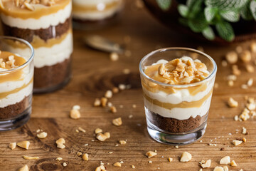 Snickers toffee cream peanut layered dessert in a glass jar on a wooden background