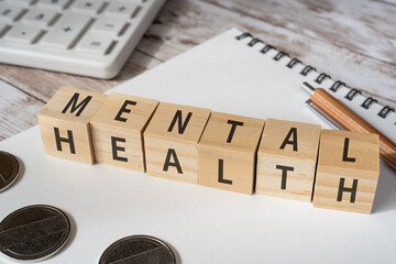 メンタルヘルスのイメージ｜「MENTAL HEALTH」と書かれた積み木、電卓、ノート、コイン