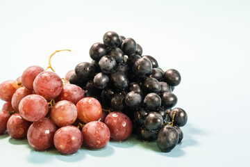 Branches of black and red grapes with water drops on a light background natural lighting.	
