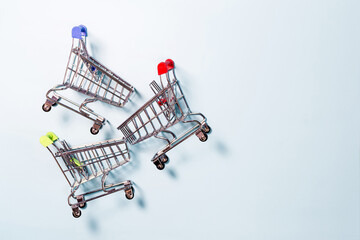 Three metal grocery baskets with colored handles on a light background top view. The concept of...
