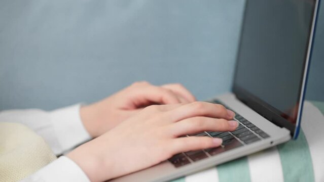 ソファーでラップトップを操作している女子高生