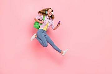 Profile photo of excited lady jump hold telephone run wear backpack earphones jacket isolated pink color background