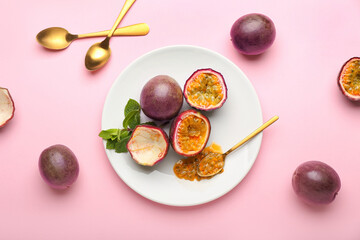 Plate with delicious passion fruits on pink background