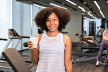 Attractive fitness African American woman finishing workout and drinking protein milk shake vitamins after training. Bodybuilding. Healthy lifestyle.