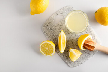 Composition with lemons, juicer and glass of juice on light background