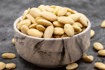 Peeled almond kernel on dark background. A bowl of almonds. close up