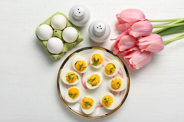 Plate with stuffed eggs on white wooden background. Easter celebration