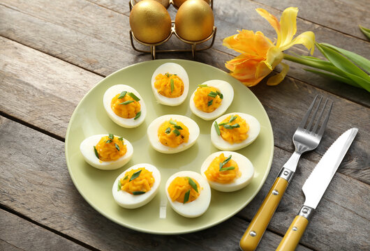 Plate and holder with eggs on wooden background. Easter celebration