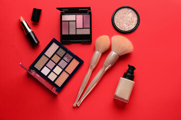 Composition with cosmetic products and makeup brushes on red background