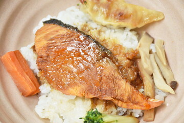 grilled salmon soy sauce with pork dumpling and vegetable topping on Japanese rice in bowl