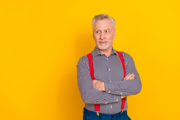 Portrait of attractive minded grey-haired man folded arms thinking copy space isolated over vibrant yellow color background