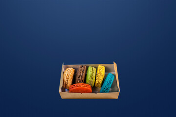 set of delicious multicolored french macaroons on a blue background. Red, green, yellow, blue and brown macaroons. Place for text.
