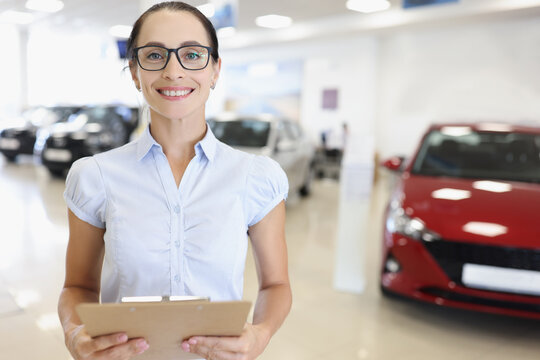 Woman car dealer with clipboard in car showroom