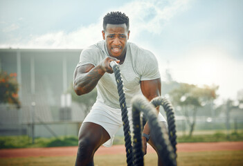 Win the battle, win the war. Cropped shot of a handsome young male athlete exercising with battle ropes outside.
