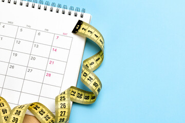 Calendar and yellow measuring tape on a blue background. Copy space for text