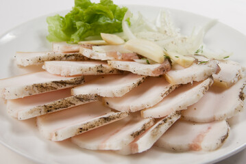 Fresh lard, sliced with greens on a white plate