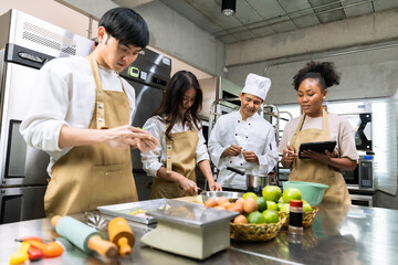 Cooking  course , senior Asian male chef in cook uniform teaches young asian and african american...