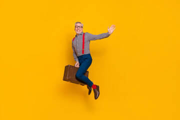 Obraz na płótnie Canvas Full body photo of flying pensioner enjoy traveling with retro valise say you hello isolated on yellow color background