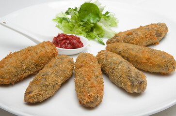 Meat patties with salad greens and parsley on a white bowl.