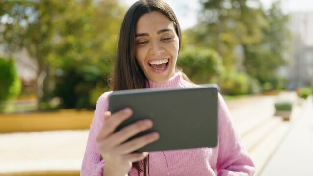 Young hispanic woman smiling confident watching video on touchpad at park
