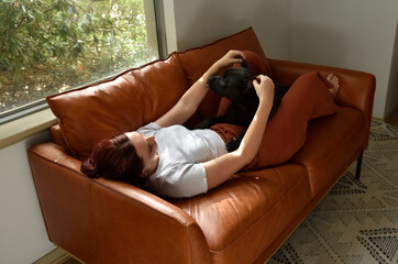 full length portrait o red haired girl wearing casual clothes, relaxing on comfortable  leather...