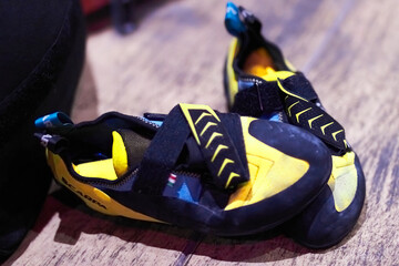 Yellow, black and blue climbing bouldering shoes on a wooden floor