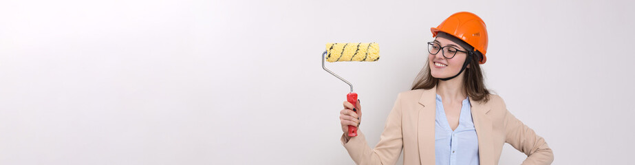 Girl engineer in an orange construction helmet with plastering painting tools in her hands on a white background.