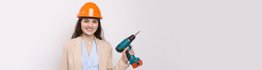 Girl engineer in an orange construction helmet with a screwdriver and a hammer on a white background.