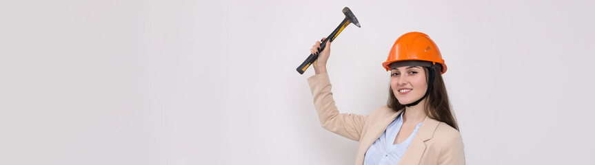 Girl engineer in an orange construction helmet with a hammer on a white background.