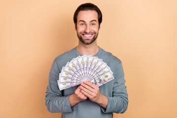 Photo of young cheerful man wealthy win lottery ecstatic benefit profit isolated over beige color...