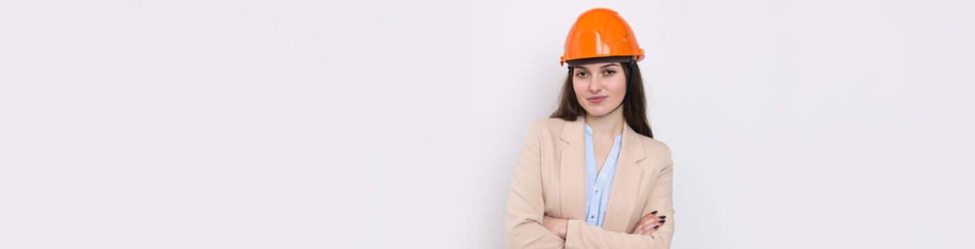 A girl architect in a suit and an orange construction helmet stands on a white background.