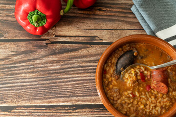 picture from above of a clay duck with lentil soup and red peppers on a wooden table. Healthy food with high vegetable protein value