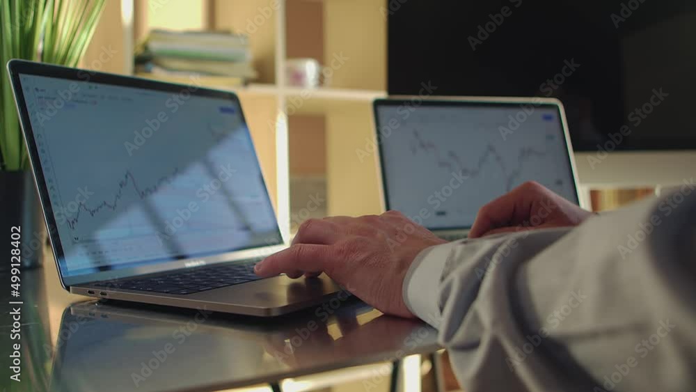 Poster a trader walks up to two laptops displaying charts of the bitcoin exchange and starts working. close