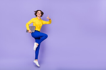 Fototapeta na wymiar Full size photo of cool millennial brunette lady jump thumb up with laptop wear shirt trousers shoes isolated on purple background