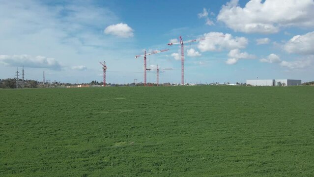 cranes at green fields in blu sky at southern district city sderot