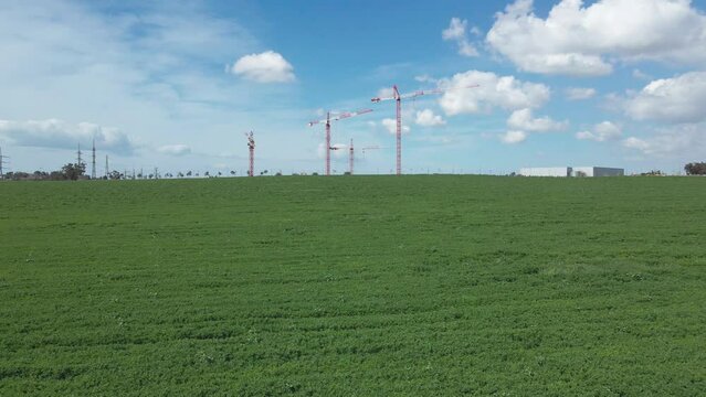 cranes at green fields in blu sky at southern district city sderot