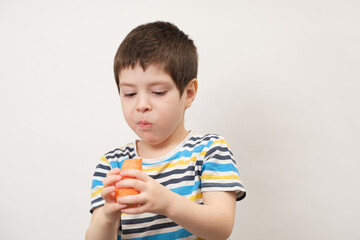 A 4-year-old boy eats carrots on a white background. Hard vegetables for dental health in children.