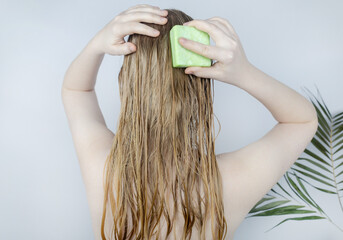 Solid hair shampoo. Close-up of a blonde girl in the bathroom, which lathers her hair with dry...