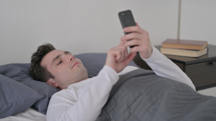 Man using Smartphone while Sleeping in Bed