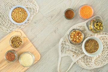 Set of vegetarian organic products in glass jars and bowls on a white wooden background. Zero waste shopping and storage farm products. Top view, copy space.