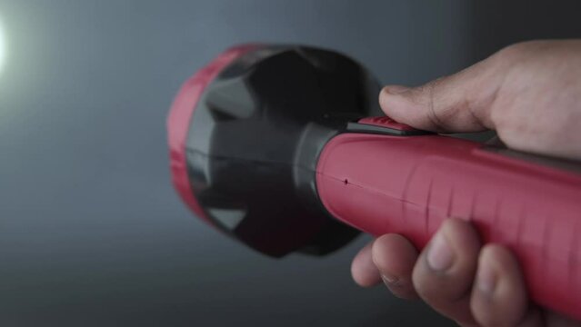 hand holding a tourch light against black background,