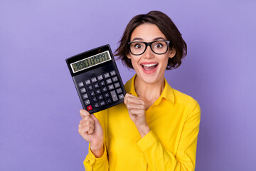 Photo of hooray millennial lady hold calculator wear yellow outfit spectacles isolated on violet color background - obrazy, fototapety, plakaty