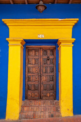 Obraz premium Woodem door in a yellow blue buiding, La Candelaria, Bogotá, Colombia