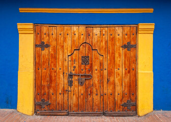 Large wooden door with locker in a blue and yellow building. La Candelaria, Bogotá, Colombia