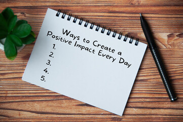 Top view of text - Ways to create a positive impact every day. With pen and plant on wooden table. Lifestyle concept