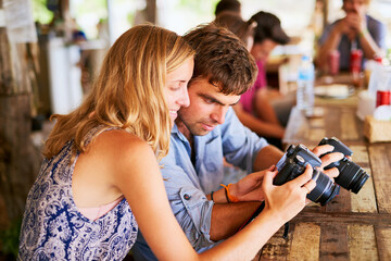 Exploring Thailand together. Shot of a young couple looking at pictures on their camera while on holiday in Thailand.