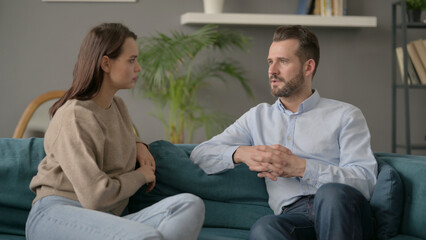 Happy Couple having Conversation while Sitting on Sofa 