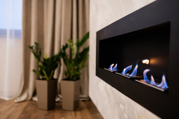 new stylish black metal fireplace with three flames burning in the house