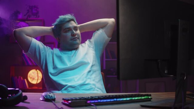 Gamer relaxing, playing computer game, streamer. Young man playing video games using backlight keyboard. Programmer or hacker working in networks, cyberspace.