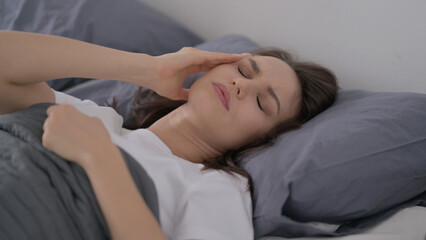 Woman having Headache while Sleeping in Bed
